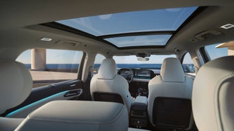 Blick vom Rücksitz auf den Innenraum eines Audi mit Panoramadach und digitalem Cockpit bei Tageslicht.