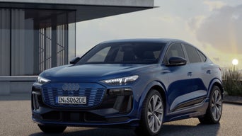 A blue Audi SQ6 Sportback e-tron parked in front of a modern house with a sky view in the background