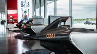 Drei Audi racing Simulator stehen im Showroom in einer Reihe; einer vorne in Nahaufnahme, zwei stehen dahinter.