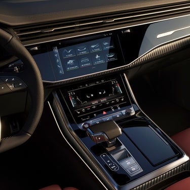 Car interior with dual touchscreen controls and a gear shift.