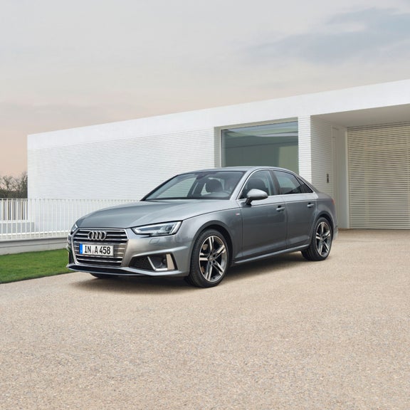 Silver sedan parked in front of a modern house with a white facade.