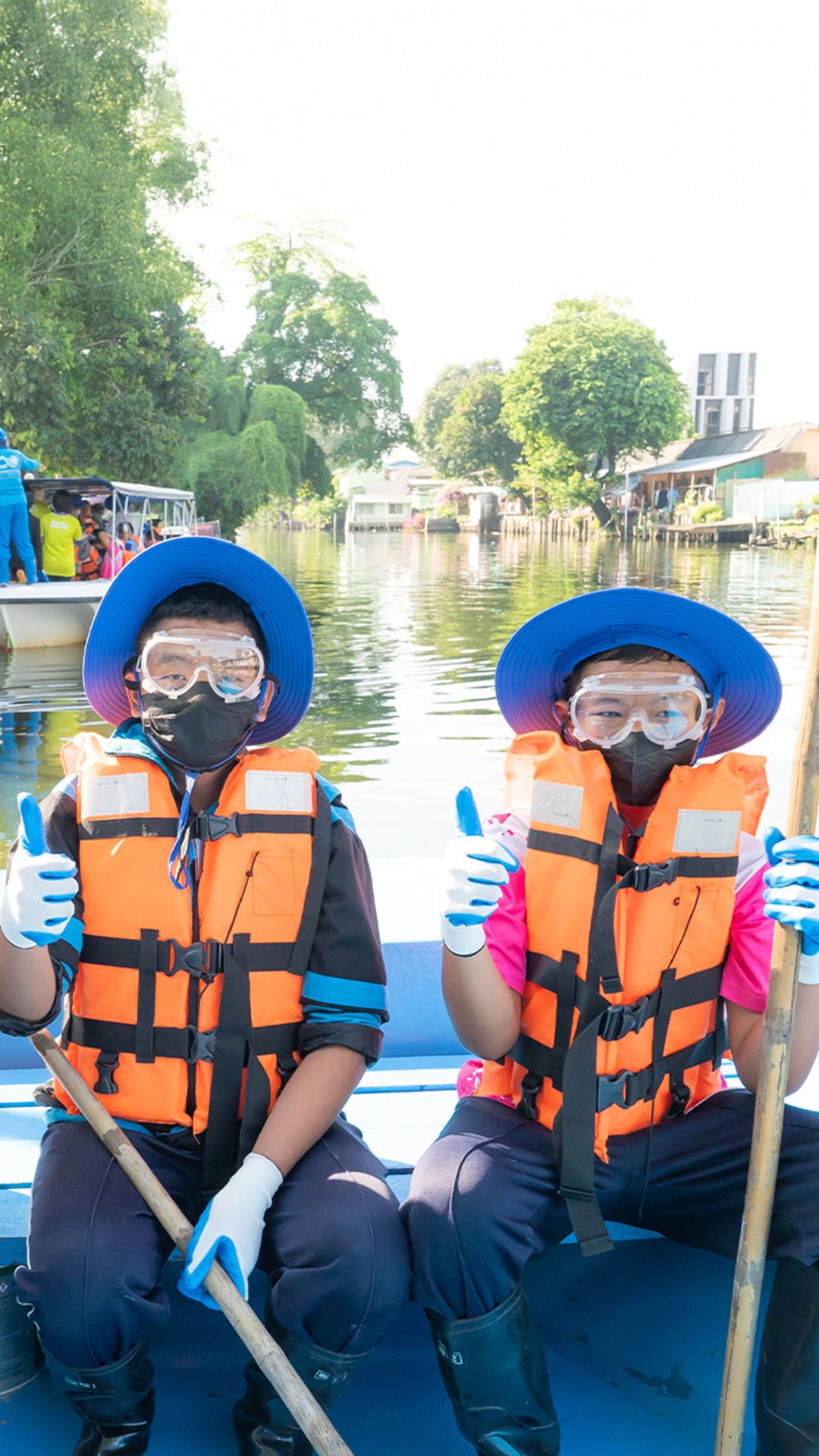 Männer mit Schwimmwesten, Taucherbrillen sind auf einem Boot und sammeln Müll aus einem Fluss ein.