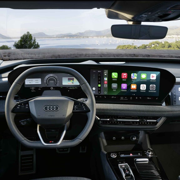 Blick aus der Fahrerperspektive auf das Lenkrad, mit dem sich dahinter befindenden Audi virtual Cockpit und das MMI touch-display im Cockpit des S6 Sportback e-tron. Das MMI touch-display zeigt die Funktion Apple CarPlay.