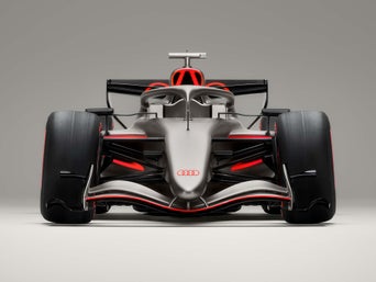 A woman gets into an Audi driving experience vehicle. The instructor stands next to the vehicle on the passenger side.