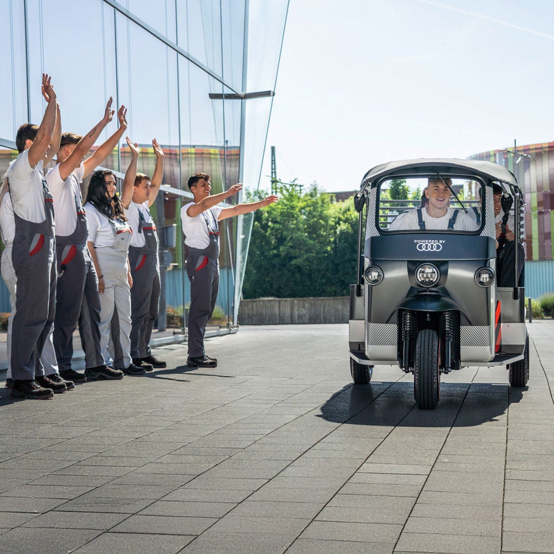 A group of trainees wave to a passing e-rickshaw.
