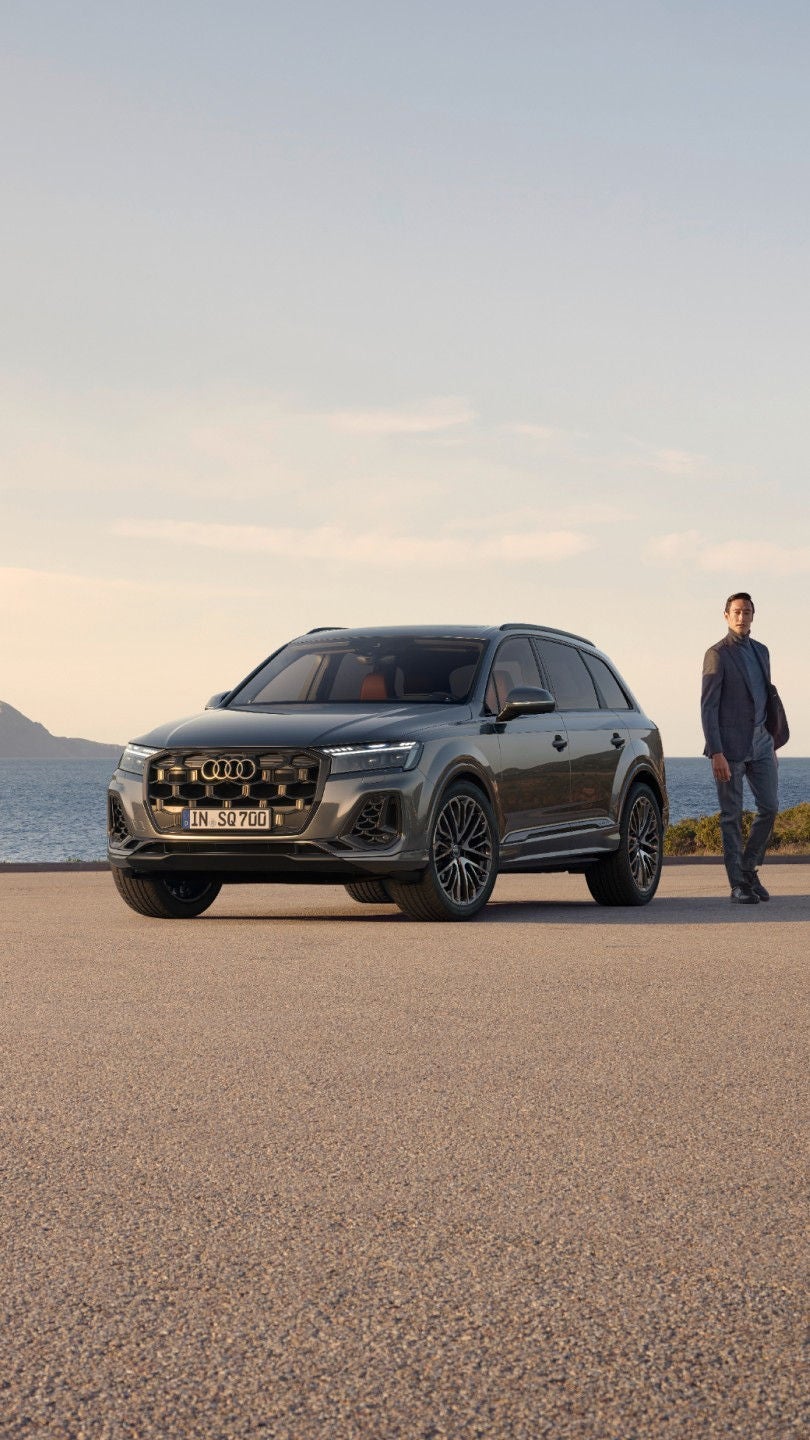 Audi SUV parked by the seaside with a man standing beside it.