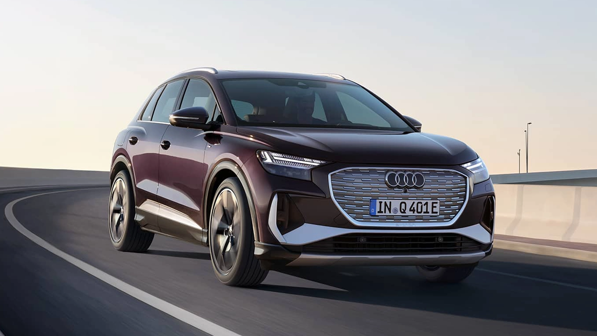 Dark purple Audi Q4 e-tron driving on a curved road with a silver grill and chrome accents.
