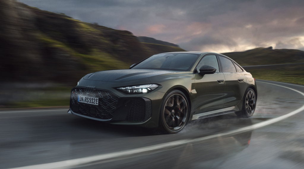 Die RS 5 Limousine schräg von vorn fährt eine Kurve auf einer Gebirgsstraße.