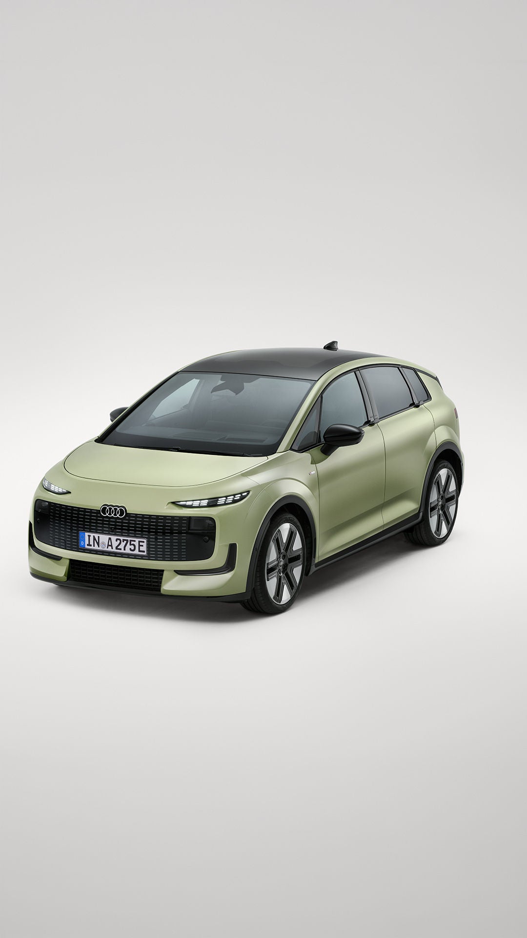 Une Audi A2 e-tron verte devant un fond de studio gris.