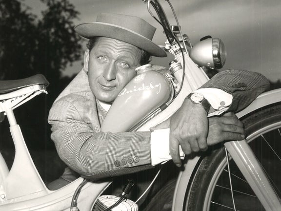 Schwarz-weiß-Aufnahme eines Mannes mit Hut, der die NSU Quickly umarmt