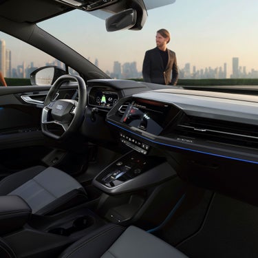 A Audi Q4 Sportback e-tron interior featuring a sleek dashboard, advanced infotainment system, and luxurious seating against a city skyline.