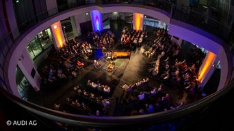 Vogelperspektive auf Musiker im Zentrum von Zuschauern im Audi Forum
