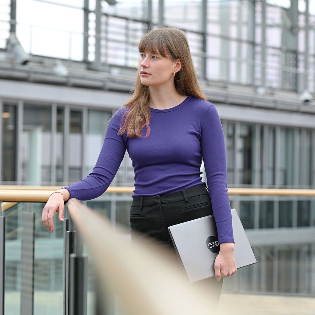 Josee steht in einem Treppenhaus und ist an ein Geländer gelehnt