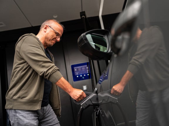 A man plugs the CCS connector into his vehicle