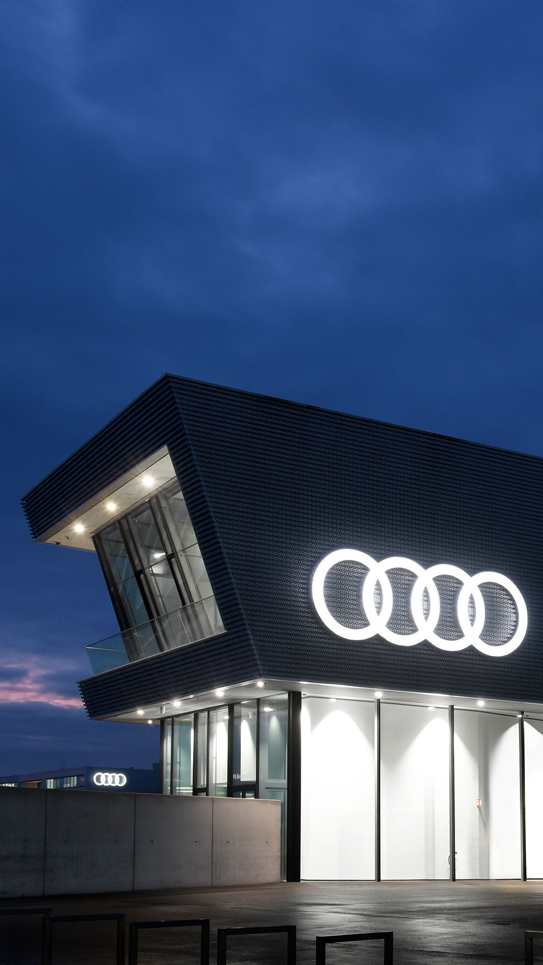 Grå byggnad med stora fönster och en vit Audilogga