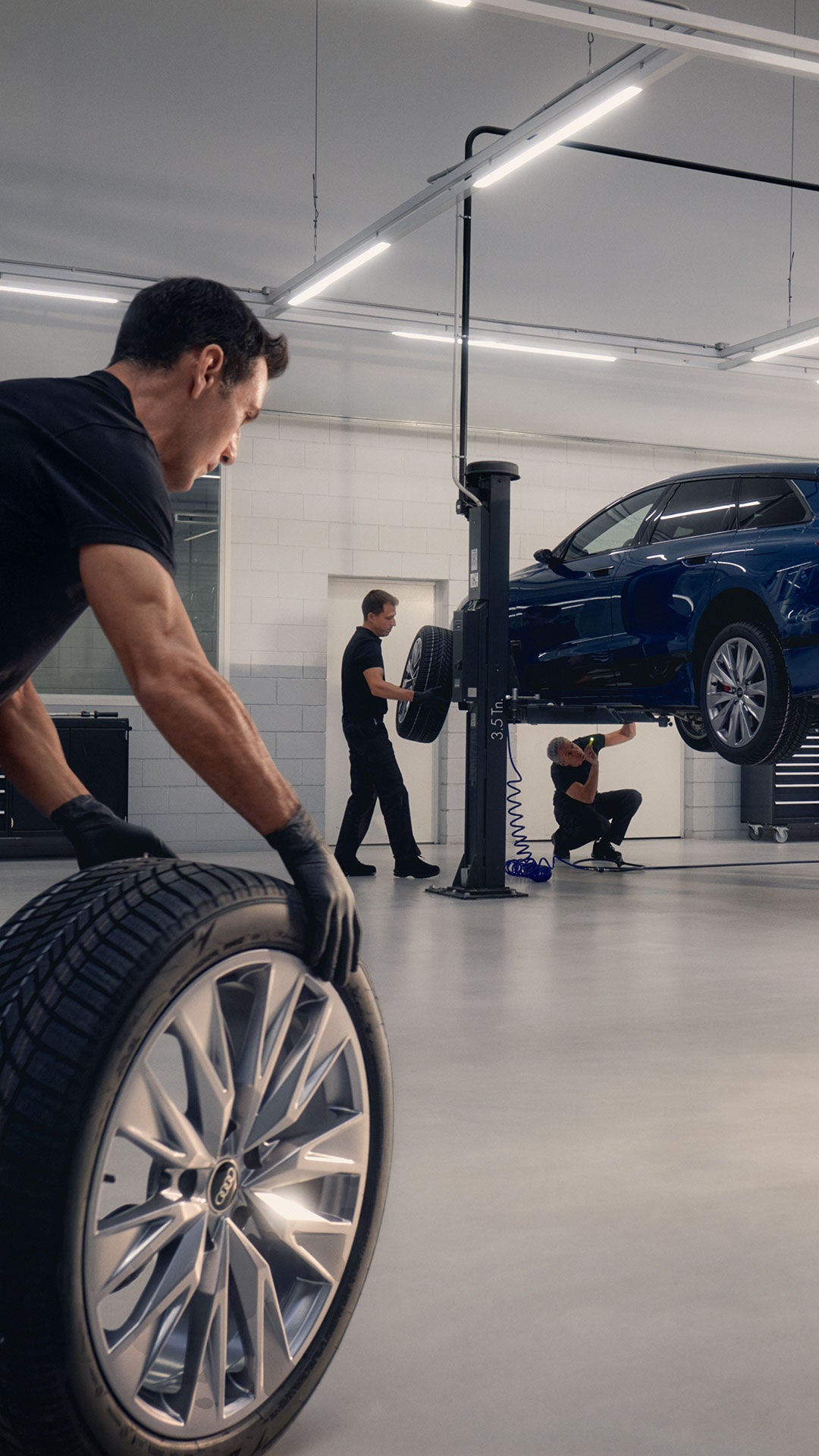 Mann schiebt Reifen in Garage herum und A6 e-tron ist auf einer Hebebühne
