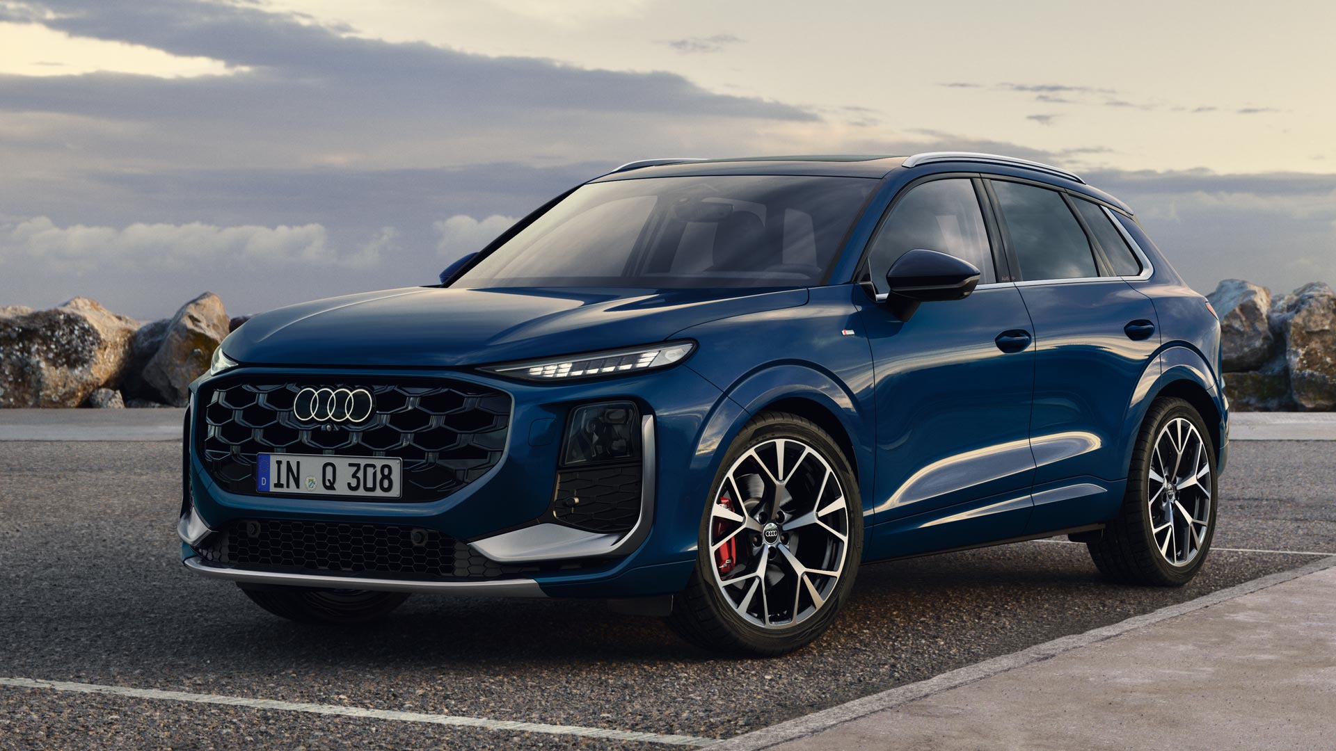 The Q3 SUV in Ascariblau metallic, viewed from the side, parked on a coastal road.