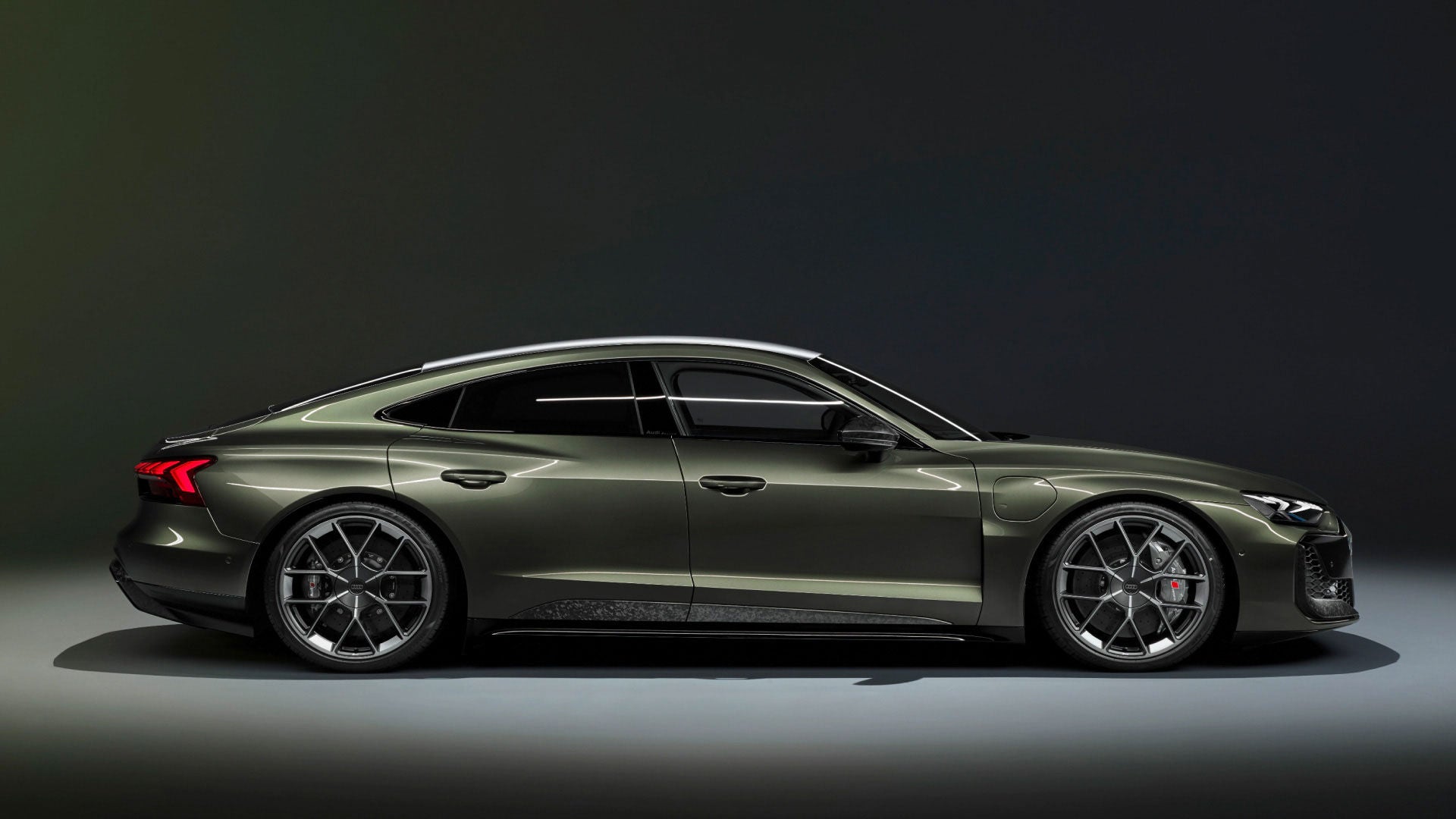 Seitliche Studioaufnahme eines dunkelgrünen Audi e-tron GT mit sportlichem Design und markanten Felgen.