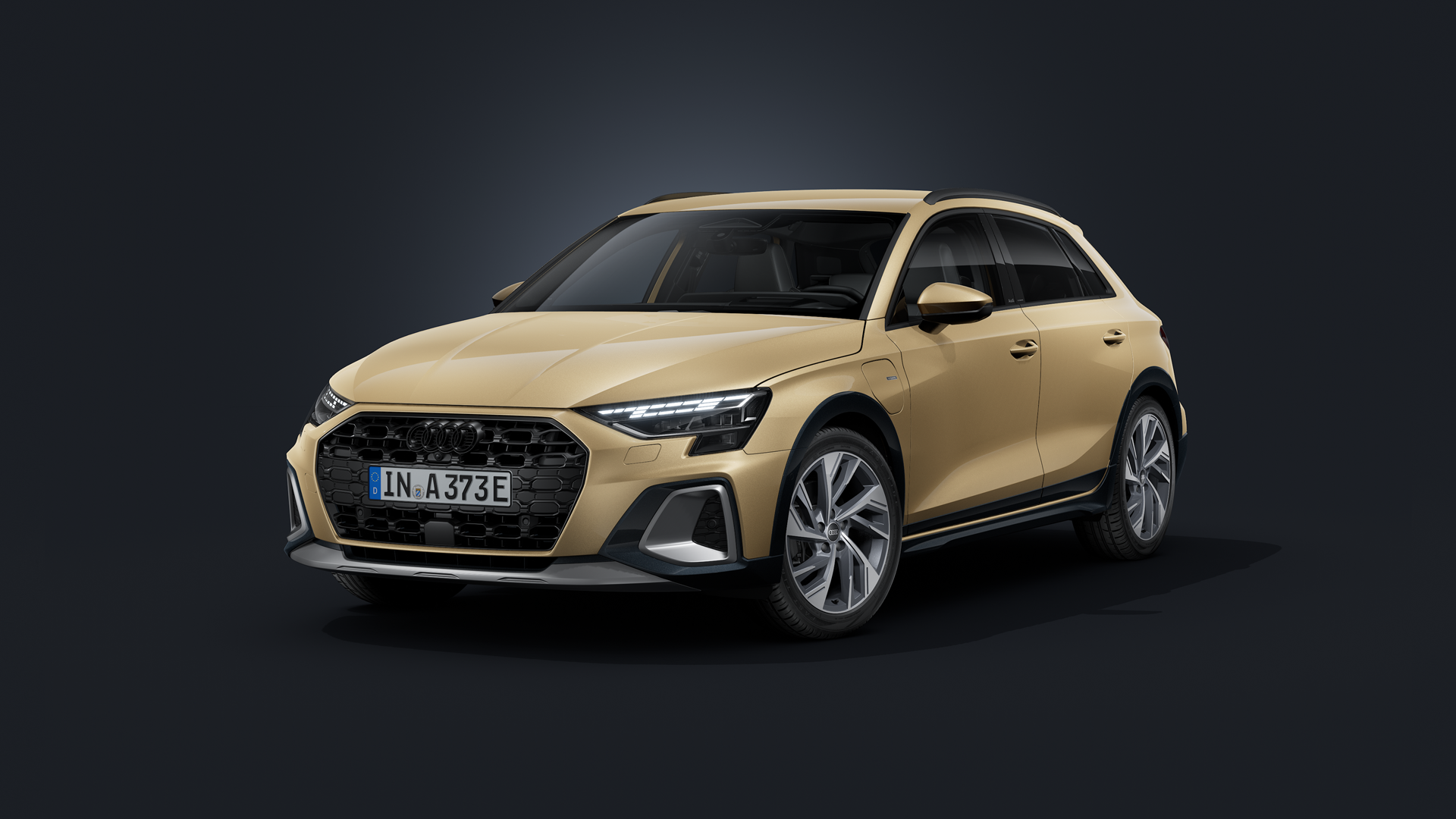 Der Audi A3 allstreet e-hybrid mit Individuallackierung Audi exclusive in Sandbeige Perleffekt schräg von vorne auf dunklem Hintergrund.