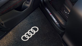 Die Autotür projiziert ein Licht auf den Boden in der Form von den Audi Ringen
