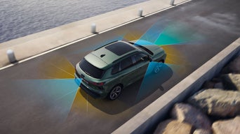 Vogelperspektive eines Audi Q3, der über eine Hafenstraße fährt. Rechts von ihm sind Felsen, links die Kaimauer und das Wasser. Im Hintergrund ist ein Teil eines festgemachten Schiffes zu sehen.