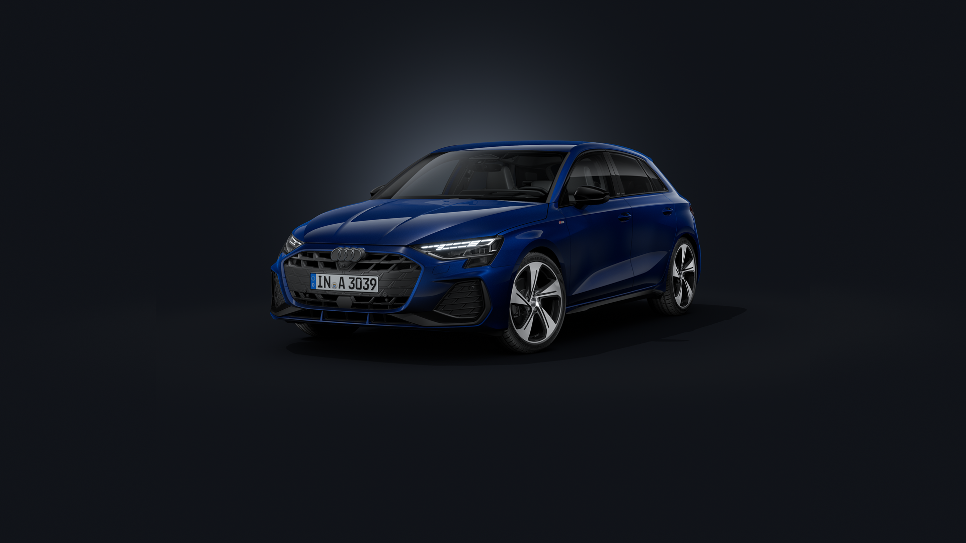 De Audi A3 Sportback, van voren gezien vanuit een hoek tegen een donkere achtergrond.