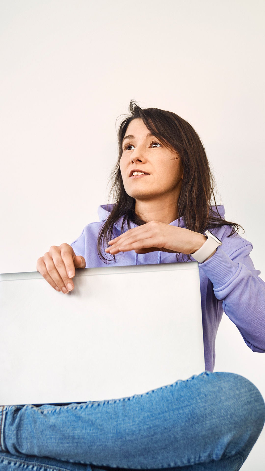 Sevgi sits with her laptop on her lap and says something. A colleague sits in front of her