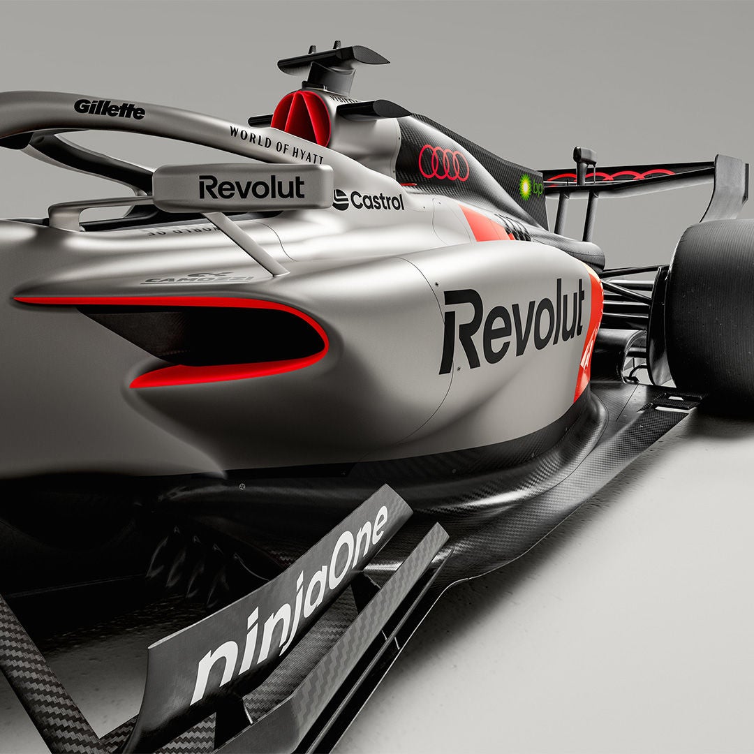 Nahaufnahme der Seitenpartie eines silbernen Audi-Formel-1-Wagens mit roten Akzenten und Sponsoren-Logos.
