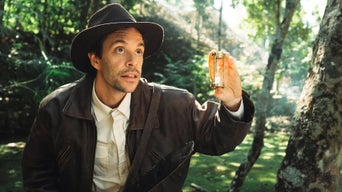 Tobi überprüft in einem Wald etwas mithilfe einer Sanduhr.