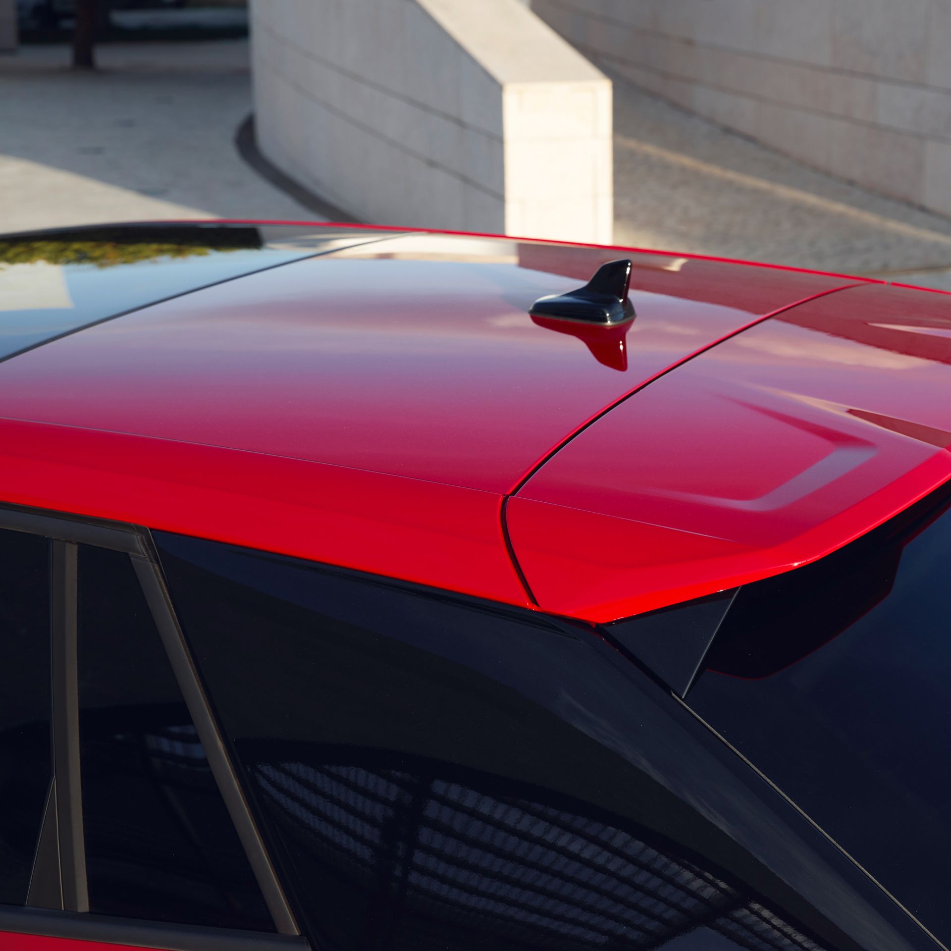Close-up of a red car roof with a fin-shaped antenna.