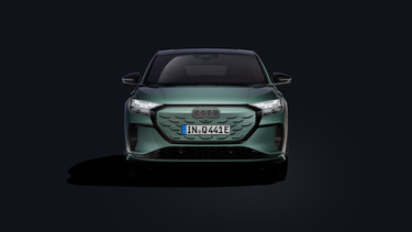 Der Q4 Sportback e-tron in Frontansicht auf dunklem Hintergrund stehend.