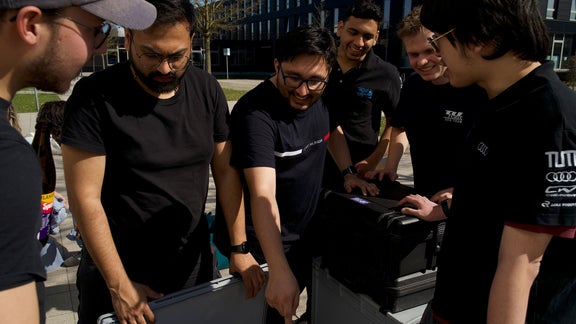 A few men in black shirts stand around a device