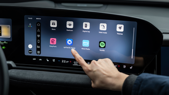 Das zentrale MMI-Display eines Audi zeigt die Integration verschiedener Apps wie EasyPark und ryd. Ein Finger tippt auf das Symbol für die jeweilige App.