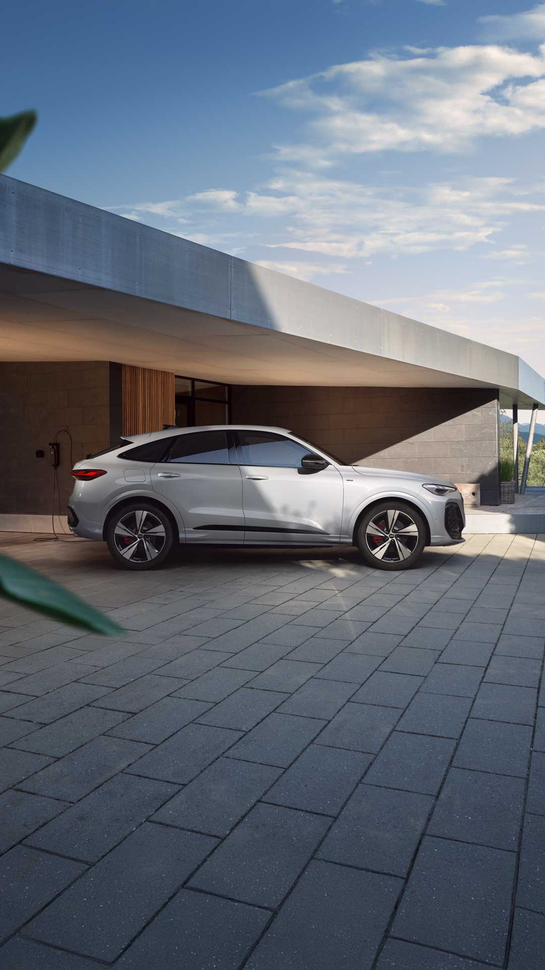 Una Audi Q5 Sportback e-hybrid bianca vista laterale di fronte a una casa