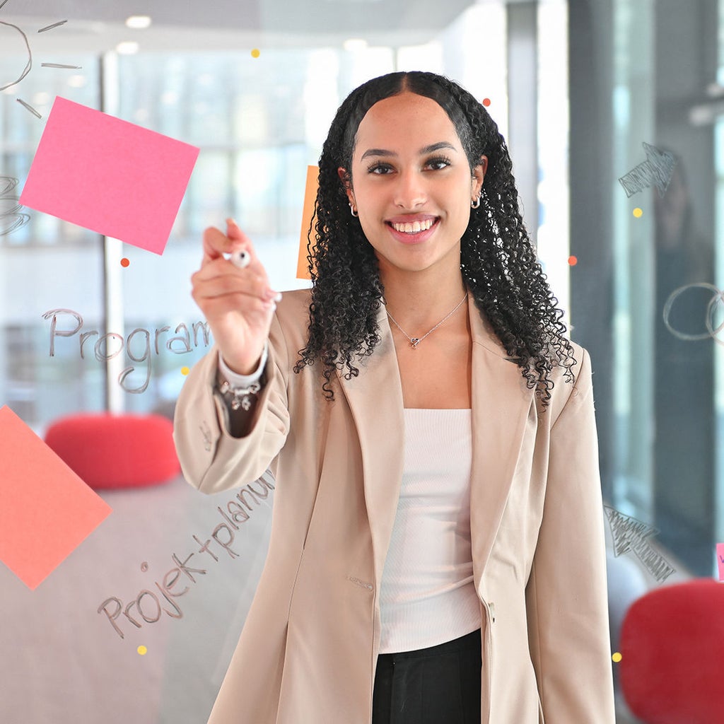 Lisa-Marie lacht in die Kamera und hält einen Stift an eine Scheibe mit Klebezetteln