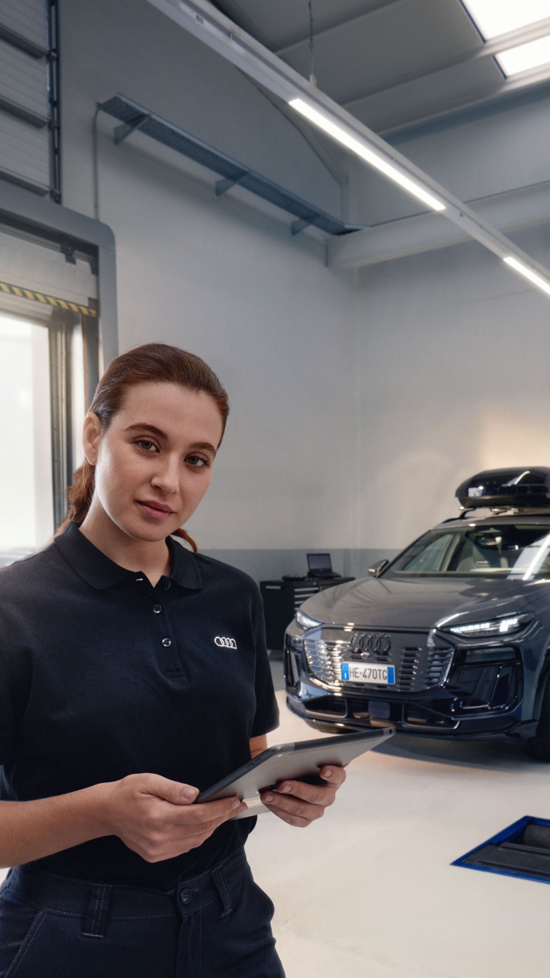 tecnico di officina consulta il computer, dietro di lui un auto Audi