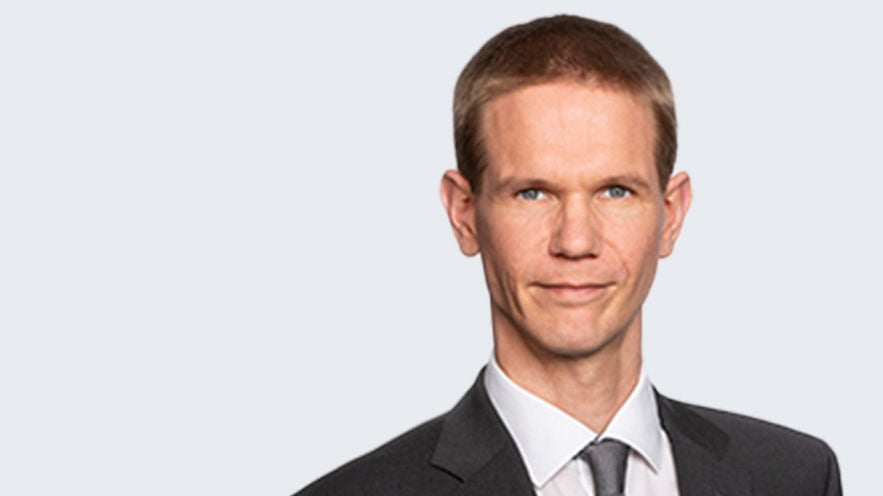 Prof. Dr. Eric Wagner: Porträt eines Mann mit kurzem Haar im Anzug vor grauem Hintergrund.