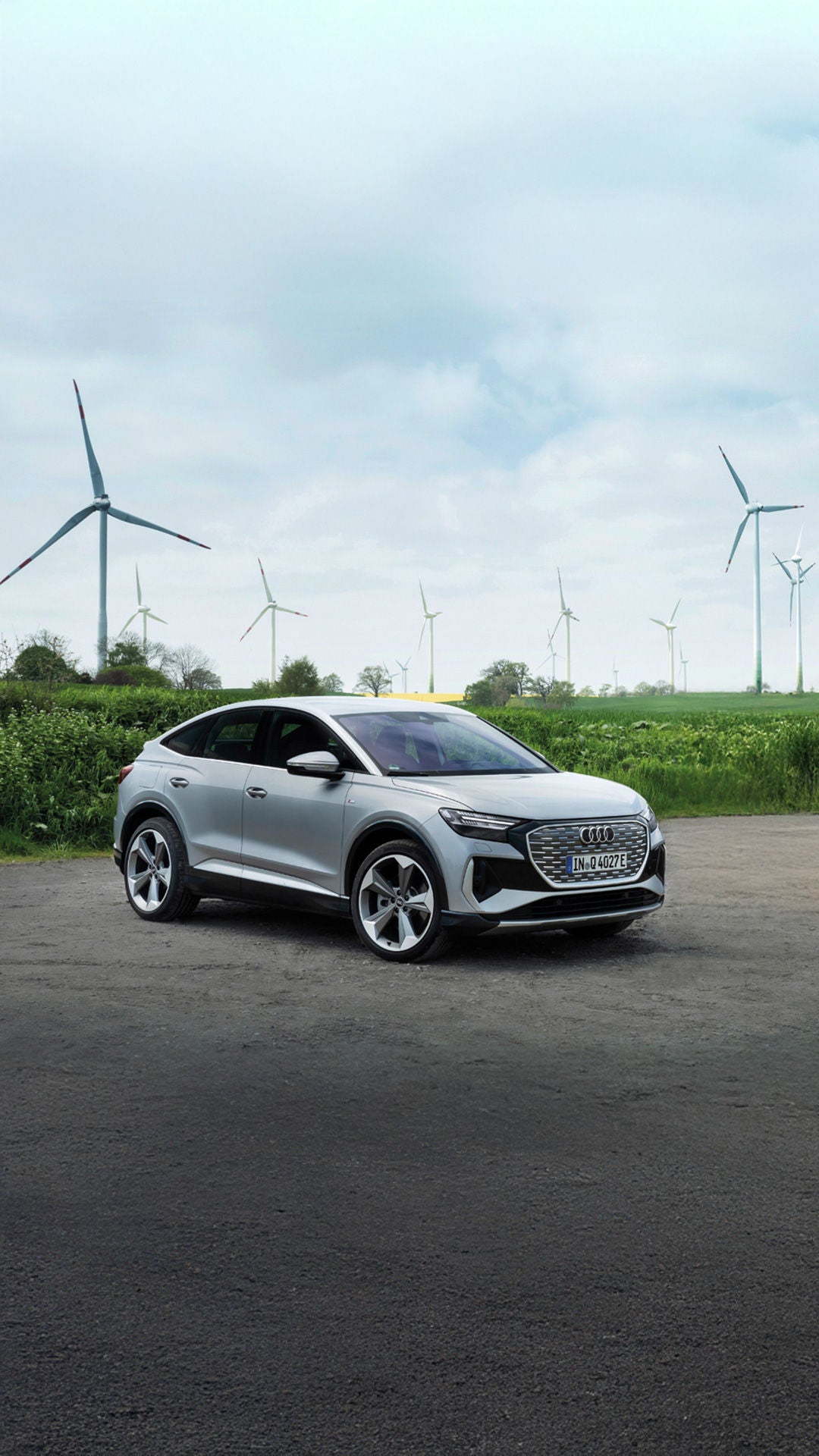 Mehrere Audi Q4 Sportback e-tron Modelle vor einer Wiese mit Windrädern