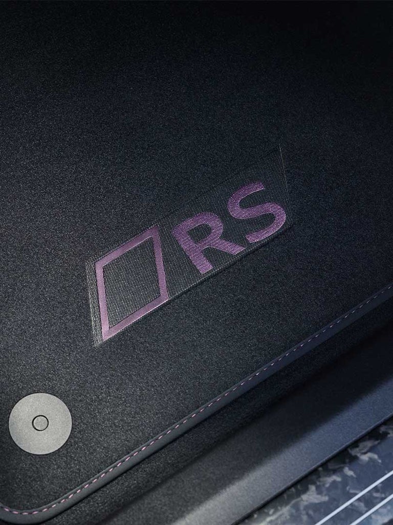 Nahaufnahme eines schwarzen Teppichs im Audi RS e-tron GT mit lila gesticktem „RS“-Logo.
