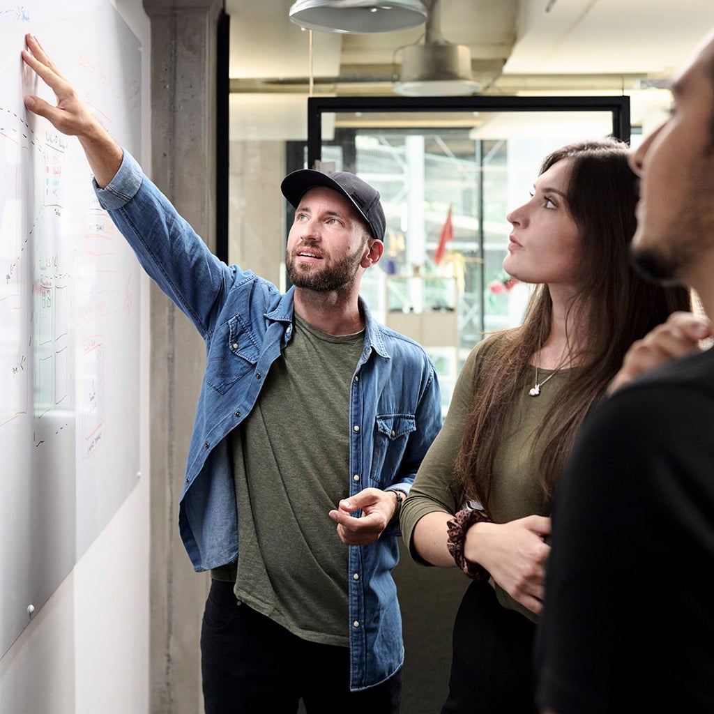 Sebastian Kister zeigt seinen Kollegen etwas an einem Whiteboard.