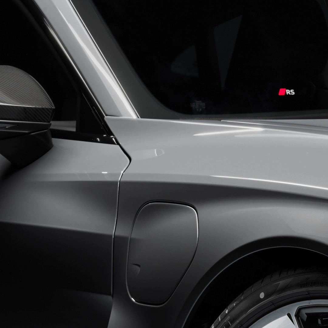 Close-up of the RS e-tron GT's side panel, door mirror, and tyre, with a blacked-out window featuring a red and white 'RS' logo.