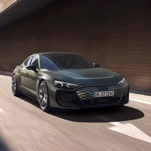 Sleek green Audi car driving in a sunlit tunnel, showcasing modern design and dynamic motion. The mood is energetic and luxurious.