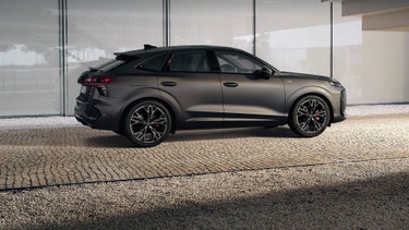 El Q3 Sportback está aparcado delante de la barandilla de las escaleras de un edificio, en un camino pavimentado.