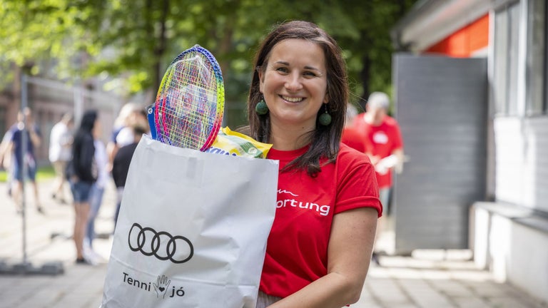 Employee with a white bag bearing the Audi logo, from which badminton rackets protrude