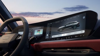 Close-up van de cockpit van een Audi, genomen vanaf de passagierszijde.  De focus ligt op het middendisplay.