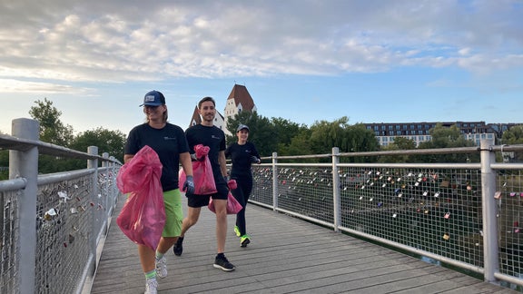 Drei Personen joggen über eine Brücke