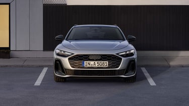 Der A5 Avant steht im Frontprofil auf einem Parkplatz vor einem Gebäude.