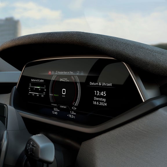 Nahaufnahme des digitalen Cockpits eines Audi S e-tron GT mit Tachometer, Batteriestatusanzeige und Datum/Uhrzeit. Das Display zeigt eine verbleibende Reichweite von 425 km und spielt das Lied „Purple Rain“.