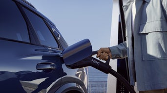 Close-up of the charging socket on the Q6 SUV e-tron, into which a man is plugging a charging cable.