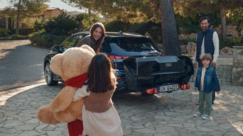 Eine Familie steht vor einem bepackten Audi mit Heckträger